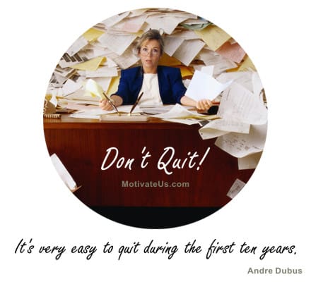 woman behind a desk with a hug stack of paper and wild hair