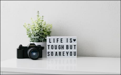 camera on a table and a sign that says Life is tough but so are you