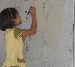 A little girl, joyfully coloring, even though she is an orphan.