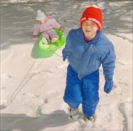 one child pulling the other up the hill - sledding