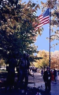 soldier in dress uniform and the American flag flying