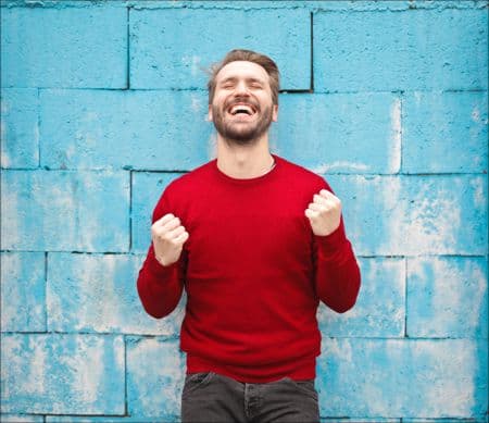 man smiling with hands in the air